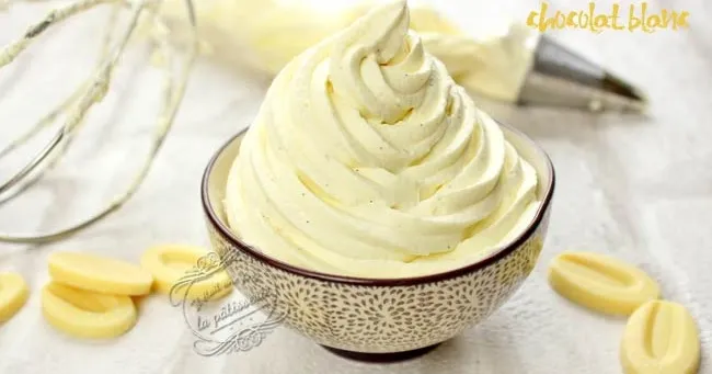 Gros plan d'une ganache au chocolat blanc onctueuse, une cuillère la soulève et elle file en nappant doucement.